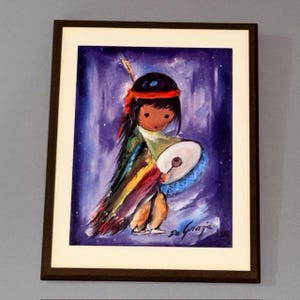 May include: Framed artwork featuring a stylized Native American child playing a drum. The painting has a purple and blue background with a starry effect. The child wears a black headband and colorful clothing. The artist's signature, "De Grazia," is visible.