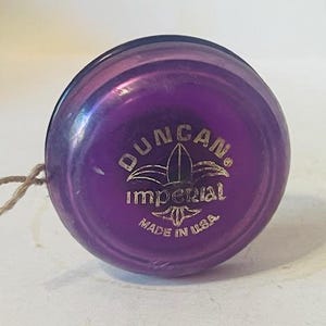 May include: Purple Duncan Imperial yo-yo with a gold logo and the text "Duncan Imperial Made in USA".