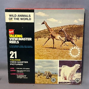 May include: A vintage "Wild Animals of the World" View-Master reel set. The box shows giraffes, elephants, and a polar bear. The text on the box reads "TALKING VIEW-MASTER REELS" and "21 TALKING VIEW-MASTER PICTURES".