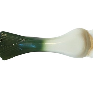Puede incluir: Un utensilio de cerámica con forma de puerro, con la parte superior verde y la inferior blanca. El puerro tiene la forma de un puerro real y tiene un agujero en la parte superior para colgarlo.