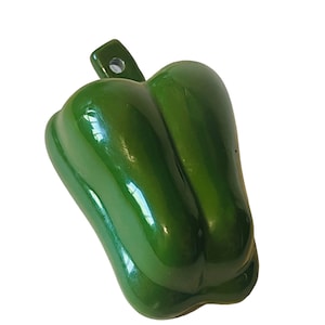 Puede incluir: Un molde para hornear con forma de pimiento verde. El molde tiene una pequeña manija en la parte superior.