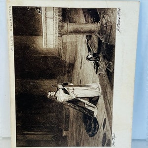 May include: A black and white vintage postcard featuring a woman in a long gown holding a sword. The postcard has the text "Wills's Cigarettes" and "A. & C. Black, Ltd." printed on it.