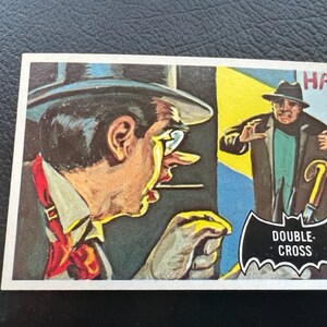 Könnte beinhalten: Eine Vintage-Comic-Karte mit einem Mann in einem Fedora und Anzug, mit dem Text "DOUBLE-CROSS" in einem schwarzen Fledermaus-Banner.
