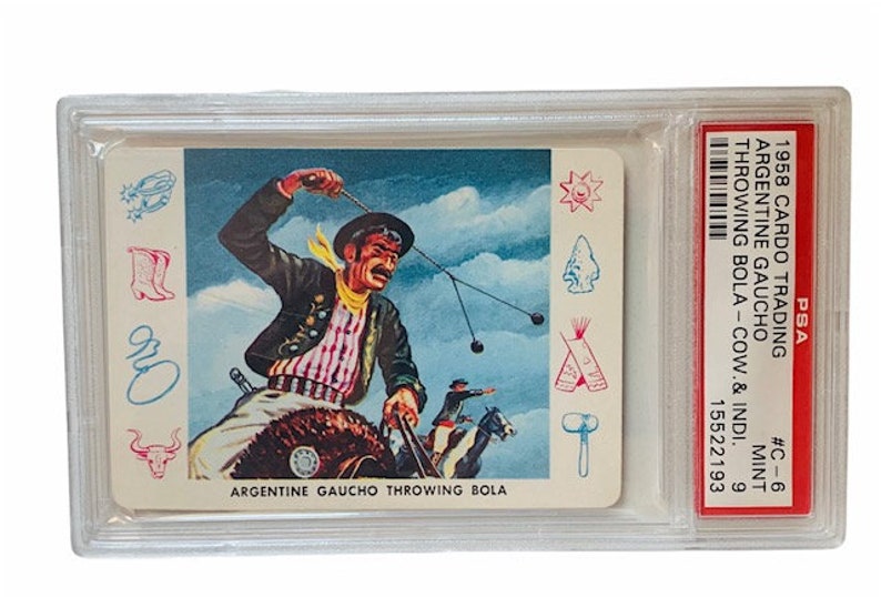 Puede incluir: Una tarjeta de colecci&oacute;n vintage que presenta una ilustraci&oacute;n colorida de un gaucho argentino a caballo lanzando una bola. La tarjeta es de la serie Carco Trading de 1958 y est&aacute; calificada como en perfecto estado por PSA. La tarjeta presenta el texto "Argentine Gaucho Throwing Bola" y "#C-6 Mint 6 15522193".