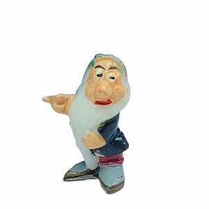 May include: A small plastic figurine of a dwarf from the Disney film Snow White and the Seven Dwarfs. The dwarf is wearing a black and red outfit and has a white beard. He is pointing to the right with his right hand.