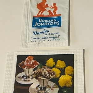 May include: Two vintage sugar packets. The top packet features the Howard Johnson's logo with a family illustration and the text "Domino Sugar melts like magic!" The bottom packet shows two ice cream sundaes in silver dishes.