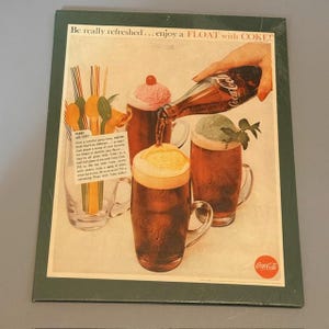Könnte beinhalten: Vintage Coca-Cola-Werbung mit Eiscreme-Getränken mit Cola. Das Bild zeigt eine Hand, die Cola in ein Glas mit einem Eiscreme-Getränk gießt, und andere Gläser mit verschiedenen Eissorten. Der Text lautet: "Be really refreshed... enjoy a FLOAT with COKE!"