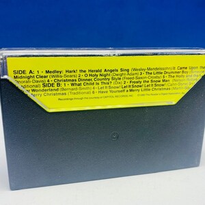 May include: A yellow cassette tape with the title "Christmas Dinner, Country Style" printed on it. The tape is labelled with the song titles "Hark! The Herald Angels Sing", "O Holy Night", "The Little Drummer Boy", "Midnight Clear", "What Child Is This?", "Frosty the Snowman", "Let It Snow! Let It Snow! Let It Snow!" and "Have Yourself a Merry Little Christmas".