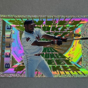 May include: A baseball card featuring Albert Belle in a Cleveland Indians uniform, mid-swing with a bat. The card has a holographic background with the word "ROOKIE" and the Topps logo.
