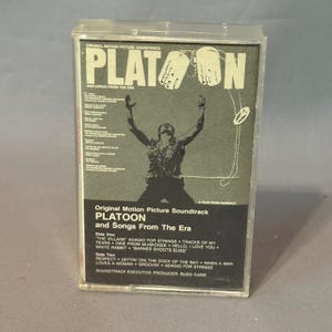 May include: A vintage cassette tape of the "Platoon" original motion picture soundtrack. The cover features a silhouette of a soldier with arms raised, the title "Platoon" in large letters, and a list of songs. The cassette is in a clear plastic case.