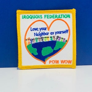 Peut inclure: Un écusson brodé jaune avec le texte "IROQUOIS FEDERATION" et "POW WOW". L'écusson présente un motif en forme de cœur avec un globe à l'intérieur et le texte "Aime ton prochain comme toi-même".
