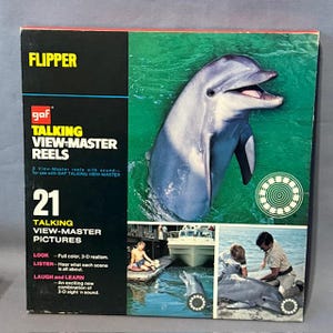 May include: A vintage Flipper Talking View-Master Reels box. The box features a large image of a dolphin in water, with the word "FLIPPER" in yellow. The box also includes the text "21 Talking View-Master Pictures" and small images of dolphins.