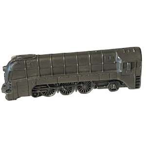 Puede incluir: Un modelo de locomotora de vapor vintage de peltre con ruedas negras y un cuerpo gris oscuro.