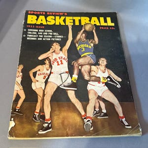 Könnte beinhalten: Vintage Basketball-Magazin-Cover von Sports Review's aus dem Jahr 1953. Das Cover zeigt eine dynamische Illustration von Basketballspielern in Aktion. Der Titel des Magazins steht in großen gelben Buchstaben, mit dem Preis von 50 Cent oben rechts.
