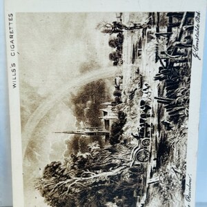 May include: A black and white vintage postcard featuring a landscape scene with a church steeple, trees, and a rainbow. The postcard is for Wills's Cigarettes and has the text "The Rainbow" and "J. Constable, R.A." printed on it.