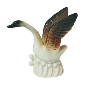 May include: White ceramic swan figurine with brown and black wings outstretched, standing on a wave-like base.