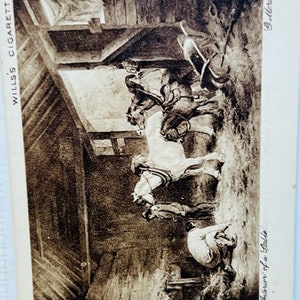 May include: A black and white photograph of a stable interior with two horses and a person. The image is from a vintage Wills's Cigarettes card. The text on the card reads "Interior of a Stable" and "G. Holland."