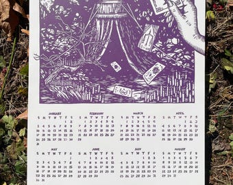 Pode incluir: Um calendário de papel branco para o ano de 2024 com uma ilustração em tinta roxa de uma tenda, uma mão segurando uma carta de tarô e um dedo apontando. Abaixo da ilustração, o calendário exibe os doze meses de janeiro a dezembro.