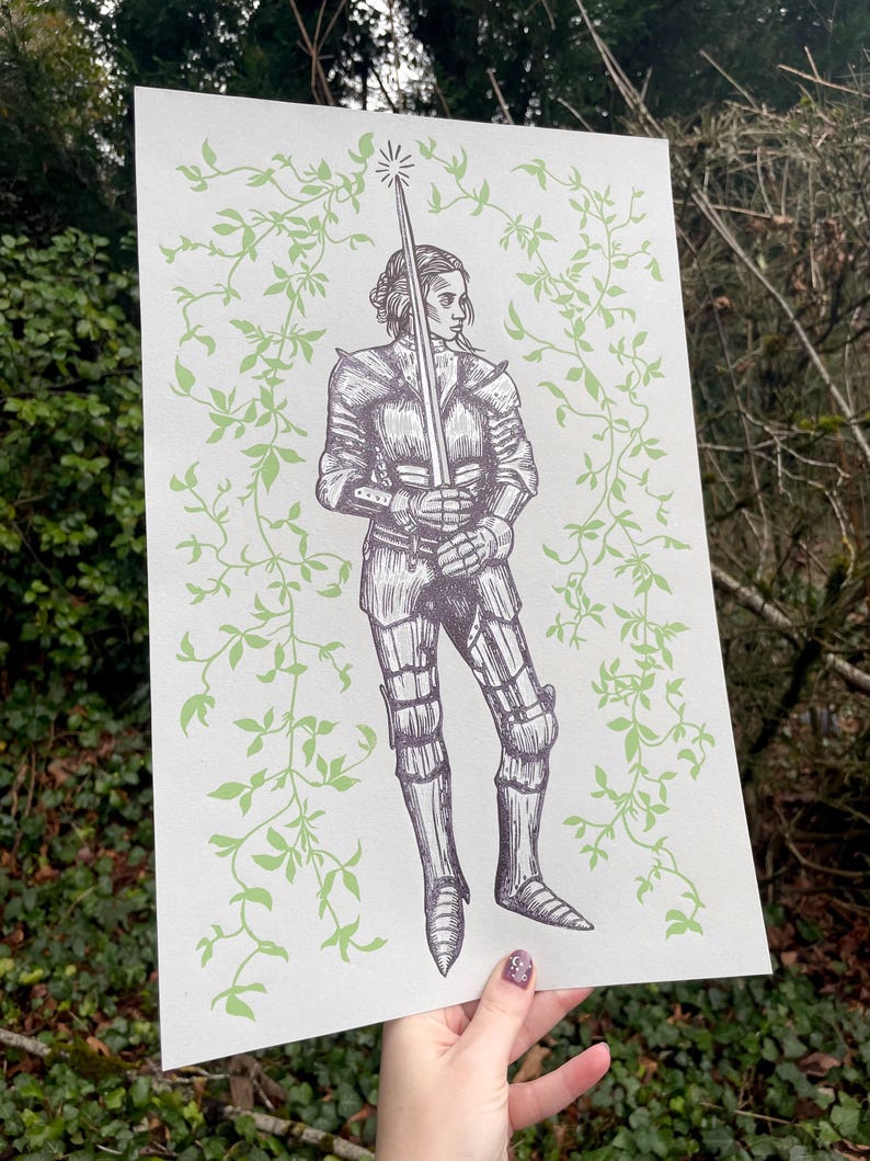 May include: A black and white illustration of a woman in armour holding a sword. The background is a light green with a vine pattern.