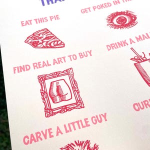 May include: A white poster with the text "THINGS I'D RATHER THAN USE AI" in purple and pink. The poster features illustrations and phrases like "EAT THIS PIE" and "FIND REAL ART TO BUY" in pink, with corresponding red illustrations.