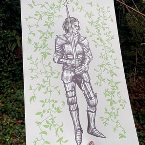 May include: A black and white illustration of a woman in armour holding a sword. The woman is surrounded by green vines.