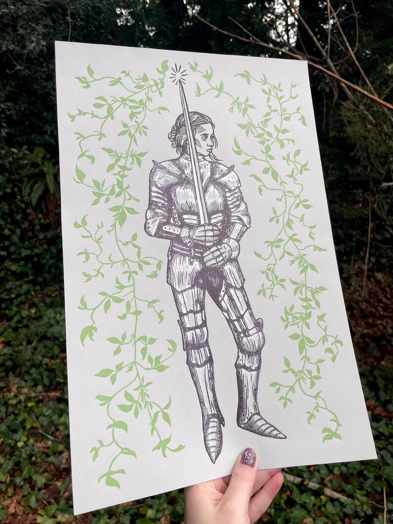 May include: A black and white illustration of a woman in armour holding a sword. The woman is surrounded by green vines.