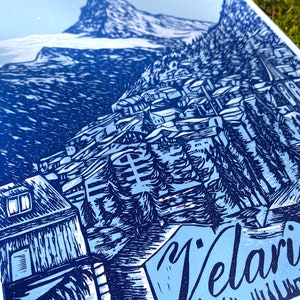 May include: A blue and white linocut print of a mountain village with the word "Velari" in the foreground.