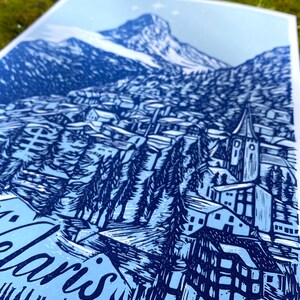 May include: A blue and white linocut print of a mountain village with a church steeple and the text "Alaris" at the bottom.