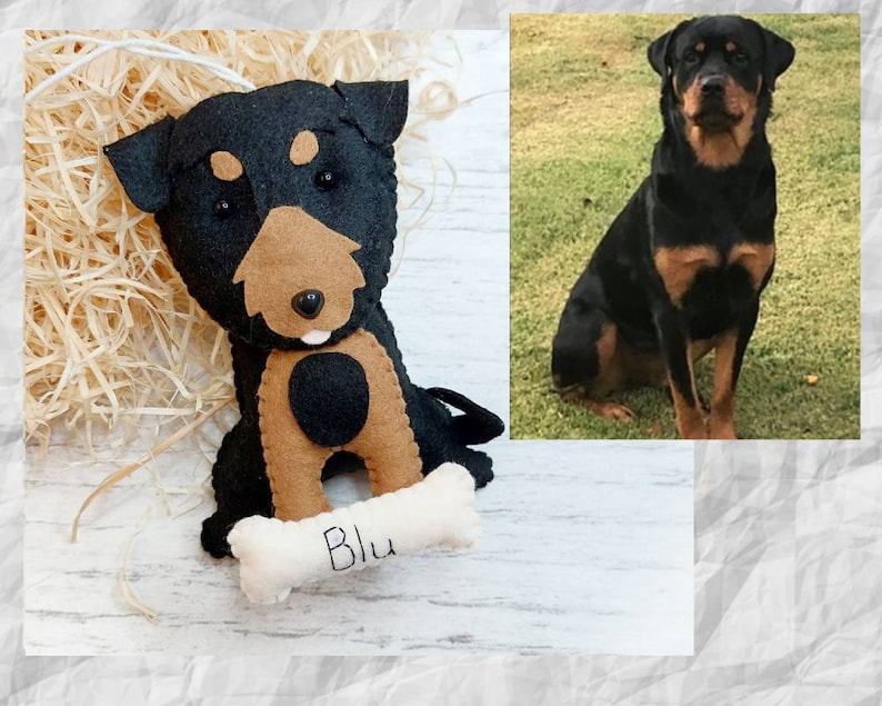 Puede incluir: Un perro de juguete de fieltro con pelo negro y marr&oacute;n, sosteniendo un hueso blanco con el nombre "Blu" bordado. El juguete es una r&eacute;plica de un Rottweiler.
