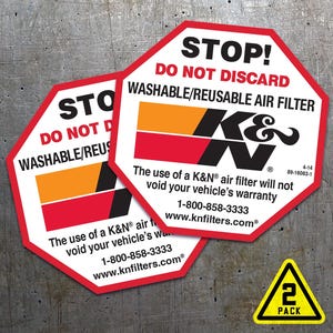 Könnte beinhalten: Zwei rote und weiße achteckige Aufkleber mit dem Text "STOP! NICHT ENTSORGEN WASCHBAR/WIEDERVERWENDBARER LUFTFILTER" und dem K&N-Logo. Die Aufkleber enthalten auch den Text "Die Verwendung eines K&N-Luftfilters führt nicht zum Erlöschen der Garantie Ihres Fahrzeugs 1-800-858-3333 www.knfilters.com". Ein gelber dreieckiger Aufkleber mit dem Text "2 PACK" befindet sich unter den achteckigen Aufklebern.