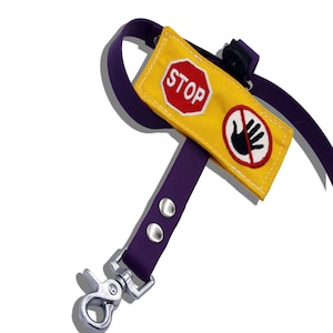 May include: Purple dog leash with a yellow fabric patch that says "STOP" and a red circle with a hand and a diagonal line through it.