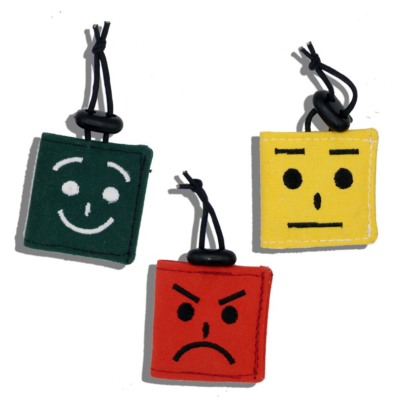 Pu&ograve; includere: Tre quadrati di tessuto con diverse espressioni facciali. Il quadrato a sinistra &egrave; verde con un viso sorridente. Il quadrato al centro &egrave; giallo con un'espressione neutra. Il quadrato a destra &egrave; rosso con un viso accigliato.