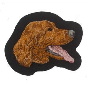 May include: Embroidered patch of a brown dog's head with its tongue sticking out, on a black background.