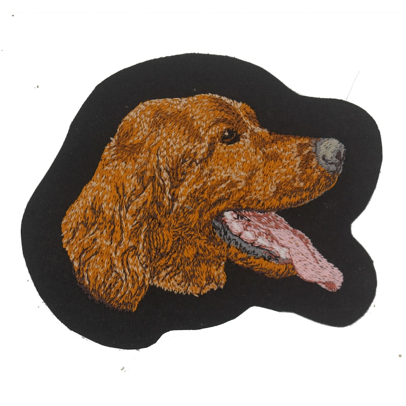 May include: Embroidered patch of a brown dog's head with its tongue sticking out, on a black background.