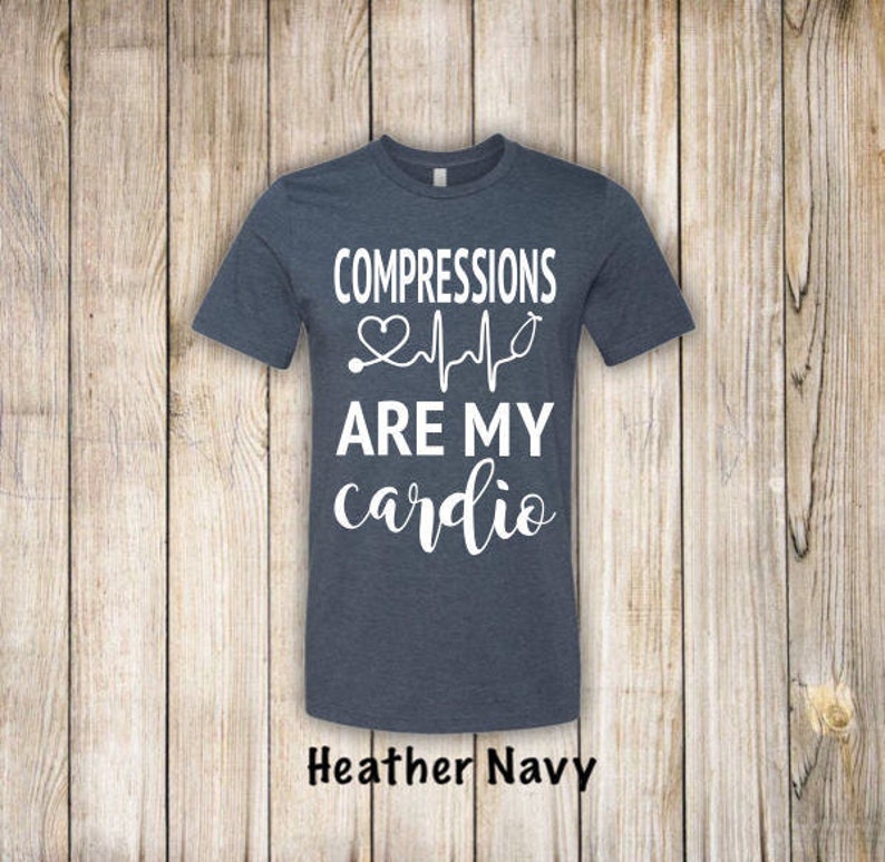 May include: A heather navy blue t-shirt with the text "COMPRESSIONS ARE MY cardio" in white. A white heart with a stethoscope and a heartbeat line are above the text.