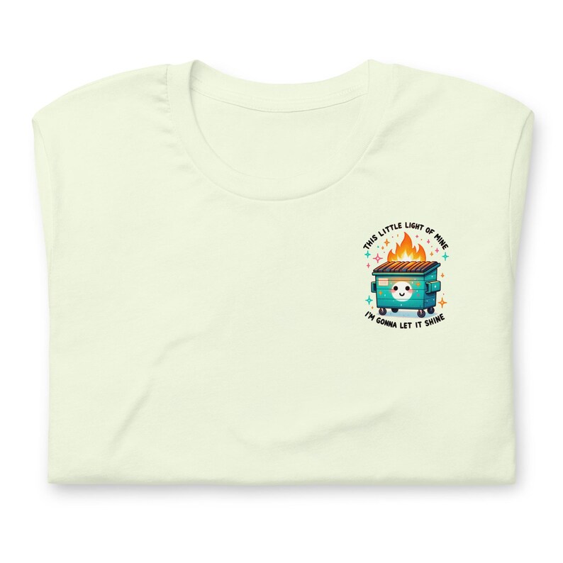 Puede incluir: Una camiseta verde claro con un gr&aacute;fico de un contenedor de basura verde en llamas con una cara blanca y el texto "This little light of mine I'm gonna let it shine".