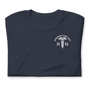 Folded navy blue ICU nurse shirt with white Intensive Care Unit RN chest graphic.