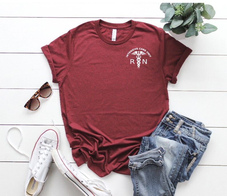 Puede incluir: Camiseta color burdeos con un gr&aacute;fico blanco de un caduceo m&eacute;dico y el texto "Intensive Care Unit RN".