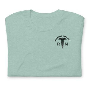 Folded dusty blue ICU nurse shirt with black Intensive Care Unit RN graphic.