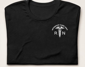 May include: A black t-shirt featuring a white graphic on the upper right chest. The graphic displays a caduceus symbol centered between the letters R and N, with the text INTENSIVE CARE UNIT arched in a semi-circle above the medical emblem.