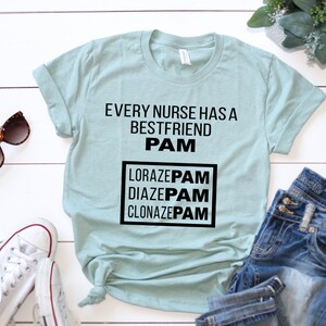 May include: A light blue t-shirt with the text "Every nurse has a best friend PAM" and a box with the text "Lorazepam, Diazepam, Clonazepam" in black text.