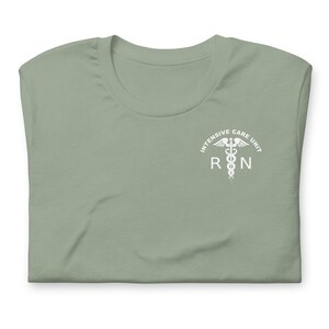 Folded sage green ICU nurse shirt with white critical care RN left-chest print.
