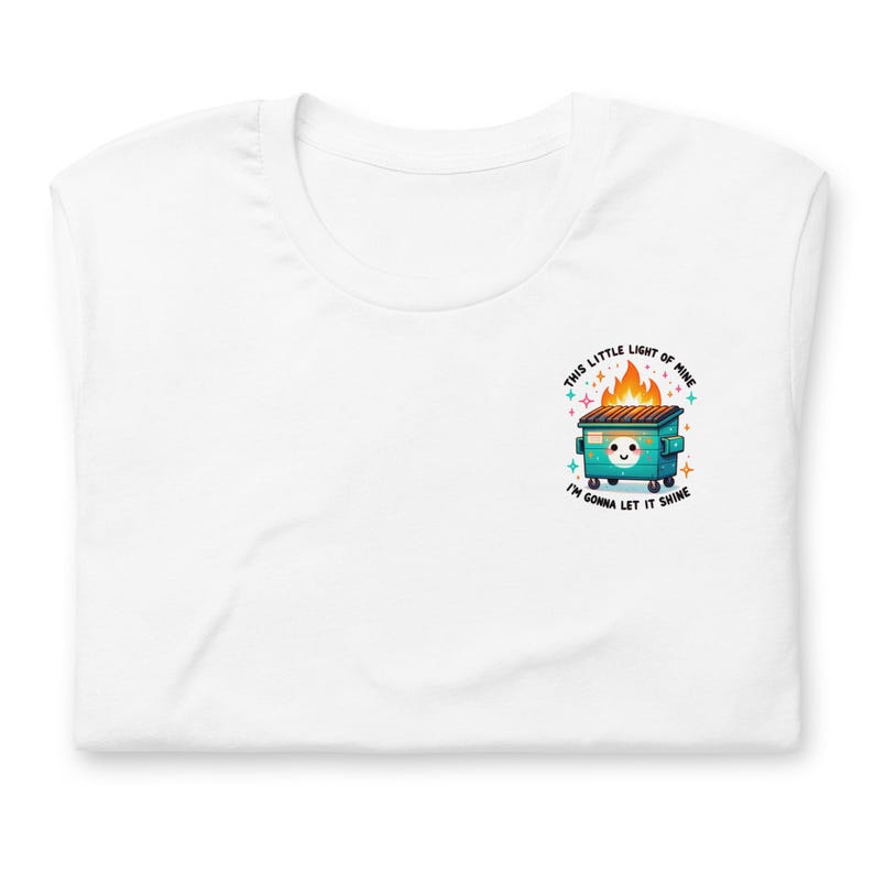 Puede incluir: Camiseta blanca con un contenedor de basura verde en llamas con una cara linda y el texto "This little light of mine I'm gonna let it shine."