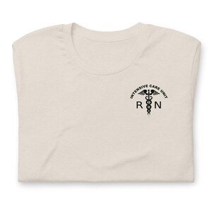 Folded natural cream ICU nurse shirt with black Intensive Care Unit RN chest design.