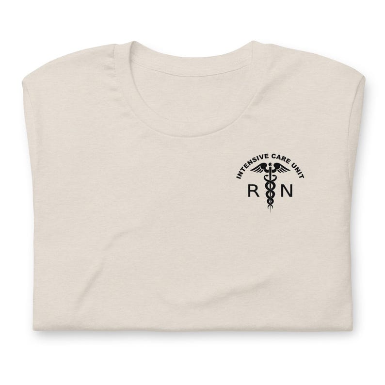 Folded natural cream ICU nurse shirt with black Intensive Care Unit RN chest design.