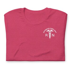 Folded berry pink ICU nurse shirt with white Intensive Care Unit RN chest print.