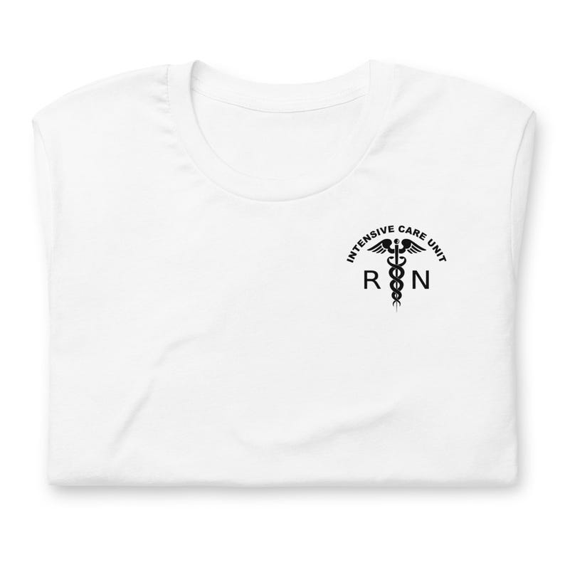 Folded white ICU nurse shirt with black Intensive Care Unit RN chest graphic.