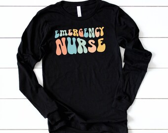 May include: Black long-sleeve t-shirt with the text "EMERGENCY NURSE" in rainbow-colored, retro-style lettering.