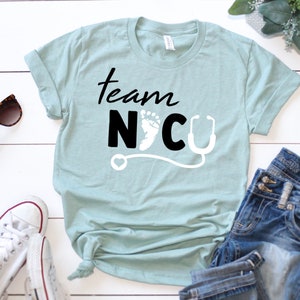 May include: A light blue t-shirt with the text "Team NICU" in black lettering. The text is accompanied by a white stethoscope and a white footprint.