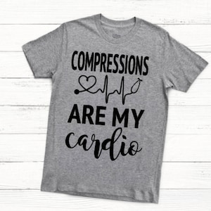 May include: Gray t-shirt with black text that reads "COMPRESSIONS ARE MY cardio" with a heart and EKG graphic.